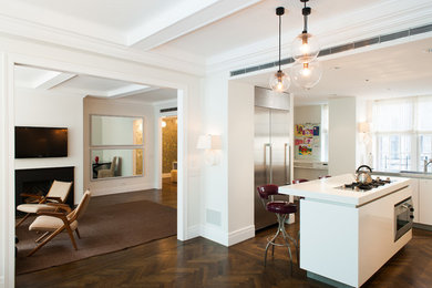 Large trendy l-shaped medium tone wood floor kitchen photo in New York with an undermount sink, flat-panel cabinets, white cabinets, stainless steel appliances, glass sheet backsplash and an island