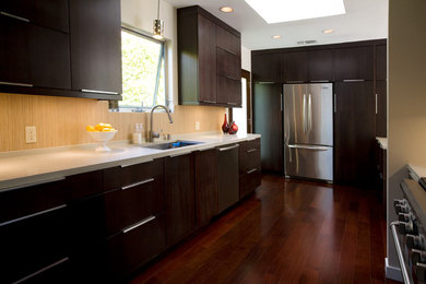 Mid-sized trendy galley medium tone wood floor eat-in kitchen photo in Los Angeles with an undermount sink, flat-panel cabinets, dark wood cabinets, quartz countertops, ceramic backsplash, stainless steel appliances and an island