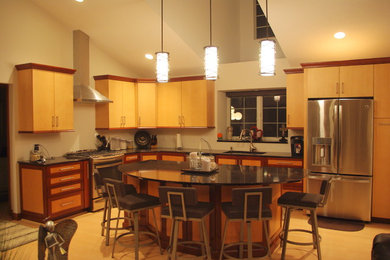 Mittelgroße Moderne Wohnküche in L-Form mit flächenbündigen Schrankfronten, Quarzwerkstein-Arbeitsplatte, Küchengeräten aus Edelstahl, zwei Kücheninseln, Unterbauwaschbecken, hellen Holzschränken und hellem Holzboden in St. Louis