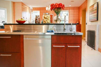 インディアナポリスにある高級な広いコンテンポラリースタイルのおしゃれなキッチン (フラットパネル扉のキャビネット、赤いキャビネット、ステンレスカウンター、メタリックのキッチンパネル、シルバーの調理設備、シングルシンク、磁器タイルの床) の写真