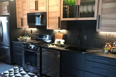 Mid-sized trendy single-wall porcelain tile and gray floor enclosed kitchen photo in New York with an undermount sink, shaker cabinets, light wood cabinets, soapstone countertops, black backsplash, brick backsplash, stainless steel appliances and no island