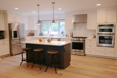 Inspiration for a large eclectic light wood floor eat-in kitchen remodel in Detroit with shaker cabinets, white cabinets, white backsplash, subway tile backsplash, stainless steel appliances and an island