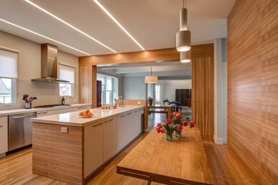 Inspiration for a mid-sized contemporary single-wall medium tone wood floor enclosed kitchen remodel in San Francisco with flat-panel cabinets, white cabinets, white backsplash, subway tile backsplash and an island