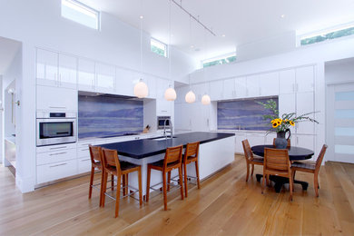 Diseño de cocina moderna extra grande con armarios con paneles lisos, puertas de armario blancas, salpicadero azul, electrodomésticos de acero inoxidable y una isla