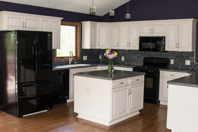 Exempel på ett mellanstort modernt kök, med en undermonterad diskho, skåp i shakerstil, vita skåp, laminatbänkskiva, stänkskydd med metallisk yta, stänkskydd i glaskakel, svarta vitvaror, mellanmörkt trägolv och en köksö