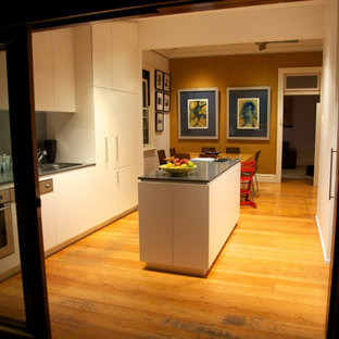 Zweizeilige, Kleine Moderne Wohnküche mit Doppelwaschbecken, flächenbündigen Schrankfronten, weißen Schränken, Quarzwerkstein-Arbeitsplatte, Küchenrückwand in Grau, Glasrückwand, Küchengeräten aus Edelstahl, hellem Holzboden, Kücheninsel, braunem Boden und grauer Arbeitsplatte in Sydney