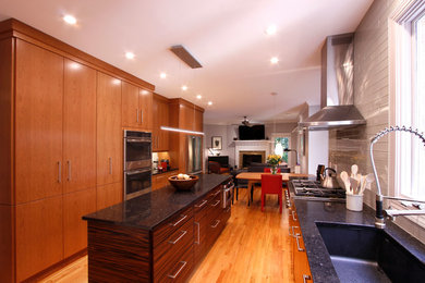 На фото: п-образная кухня-гостиная среднего размера в современном стиле с плоскими фасадами, фасадами цвета дерева среднего тона, техникой из нержавеющей стали и островом с