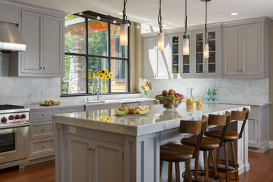 Inspiration for a large transitional l-shaped medium tone wood floor and brown floor open concept kitchen remodel in Boston with an undermount sink, recessed-panel cabinets, white cabinets, marble countertops, gray backsplash, marble backsplash, stainless steel appliances and an island