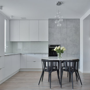 Idéer för att renovera ett mellanstort minimalistiskt grå grått kök, med en enkel diskho, släta luckor, vita skåp, laminatbänkskiva, vitt stänkskydd, glaspanel som stänkskydd, klinkergolv i keramik, integrerade vitvaror och brunt golv