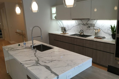 Inspiration for a mid-sized contemporary single-wall medium tone wood floor and brown floor kitchen remodel in San Francisco with an undermount sink, flat-panel cabinets, white cabinets, marble countertops, white backsplash, stone slab backsplash, stainless steel appliances and an island