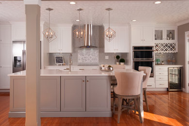 Eat-in kitchen - large transitional l-shaped medium tone wood floor and brown floor eat-in kitchen idea in Louisville with a farmhouse sink, shaker cabinets, white cabinets, quartz countertops, gray backsplash, subway tile backsplash, stainless steel appliances, an island and white countertops