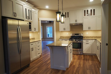 Example of a mid-sized trendy u-shaped medium tone wood floor eat-in kitchen design in Other with an undermount sink, recessed-panel cabinets, white cabinets, granite countertops, stainless steel appliances and an island