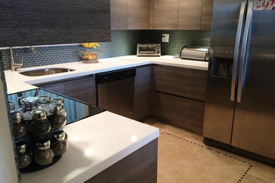 Inspiration for a medium sized u-shaped enclosed kitchen in Tampa with a single-bowl sink, flat-panel cabinets, medium wood cabinets, composite countertops, green splashback, ceramic splashback, stainless steel appliances and porcelain flooring.