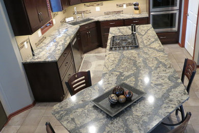 Kitchen - mid-sized transitional porcelain tile and gray floor kitchen idea in Omaha with an undermount sink, shaker cabinets, dark wood cabinets, granite countertops, beige backsplash, stainless steel appliances and an island