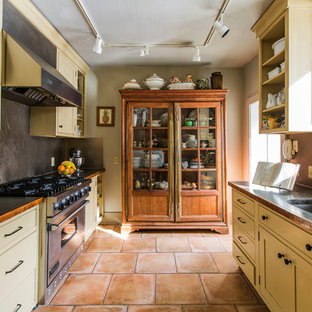 Immagine di una cucina parallela classica chiusa e di medie dimensioni con lavello sottopiano, ante in stile shaker, ante beige, top in rame, paraspruzzi grigio, paraspruzzi con piastrelle di metallo, elettrodomestici in acciaio inossidabile, pavimento in terracotta, nessuna isola e pavimento rosso