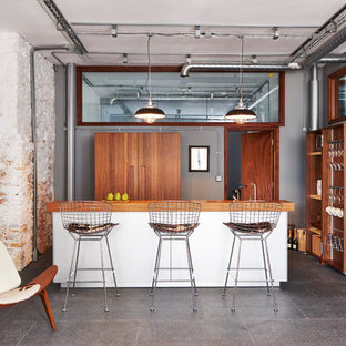 Ispirazione per una cucina parallela industriale con ante lisce, ante in legno scuro, top in legno e isola