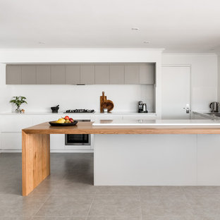 This is an example of a large modern galley kitchen in Perth with a drop-in sink, flat-panel cabinets, white cabinets, quartz benchtops, white splashback, porcelain splashback, stainless steel appliances, porcelain floors, with island and grey floor.