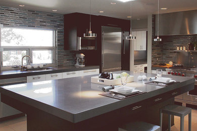 Example of a trendy travertine floor kitchen design in Albuquerque with a drop-in sink, flat-panel cabinets, dark wood cabinets, concrete countertops, blue backsplash, glass tile backsplash, stainless steel appliances and an island