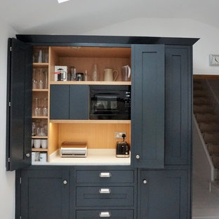 Offene, Mittelgroße Moderne Küche ohne Insel in U-Form mit Schrankfronten im Shaker-Stil, grauen Schränken, Quarzit-Arbeitsplatte, Küchengeräten aus Edelstahl, Sperrholzboden, gelbem Boden und weißer Arbeitsplatte in Hertfordshire