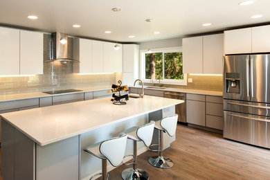 This is an example of a large classic l-shaped kitchen/diner in Seattle with a submerged sink, flat-panel cabinets, white cabinets, engineered stone countertops, grey splashback, glass tiled splashback, stainless steel appliances and an island.