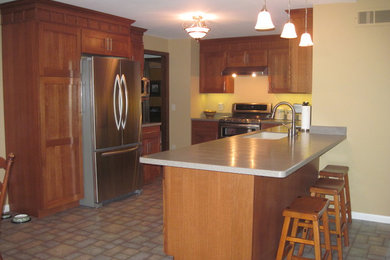 Example of a mid-sized transitional l-shaped ceramic tile eat-in kitchen design in Chicago with an undermount sink, shaker cabinets, medium tone wood cabinets, solid surface countertops, stainless steel appliances and no island