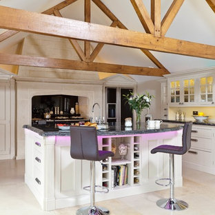 Photo of a country u-shaped kitchen in Other with with island and beige cabinets.