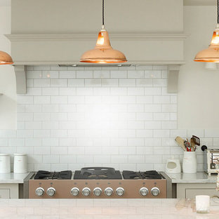Transitional kitchen ideas - Inspiration for a transitional kitchen remodel in London with an undermount sink, gray cabinets, white backsplash, subway tile backsplash, stainless steel appliances and an island