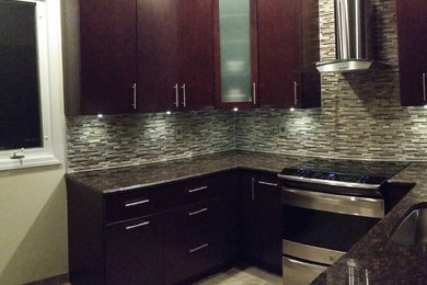 Example of a trendy u-shaped eat-in kitchen design in New York with an undermount sink, flat-panel cabinets, dark wood cabinets, granite countertops, multicolored backsplash and stainless steel appliances