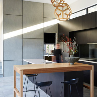 Design ideas for a contemporary galley eat-in kitchen in Brisbane with an undermount sink, flat-panel cabinets, black cabinets, black splashback, panelled appliances, with island, grey floor, porcelain floors and white benchtop.