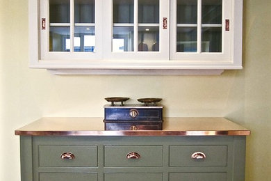 Modelo de cocina clásica grande con puertas de armario verdes, encimera de cobre, suelo de baldosas de terracota, dos o más islas y armarios con paneles empotrados