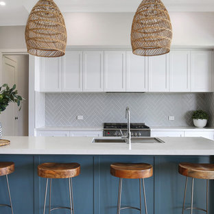 Photo of a mid-sized beach style kitchen in Wollongong with white cabinets, quartz benchtops, subway tile splashback, with island and white benchtop.