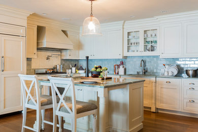 Example of a mid-sized classic u-shaped medium tone wood floor eat-in kitchen design in Other with an island, beaded inset cabinets, white cabinets, granite countertops, glass tile backsplash, paneled appliances and an undermount sink