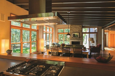 На фото: кухня-гостиная в современном стиле с столешницей из акрилового камня, светлым паркетным полом и островом