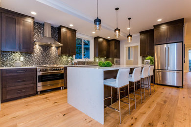 Example of a mid-sized arts and crafts l-shaped light wood floor open concept kitchen design in Vancouver with an undermount sink, shaker cabinets, dark wood cabinets, quartz countertops, multicolored backsplash, glass tile backsplash, stainless steel appliances and an island