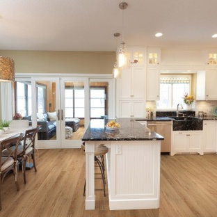Mid-sized contemporary eat-in kitchen ideas - Example of a mid-sized trendy l-shaped vinyl floor and beige floor eat-in kitchen design in Sacramento with a farmhouse sink, shaker cabinets, white cabinets, granite countertops, white backsplash, stone tile backsplash, stainless steel appliances and a peninsula
