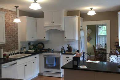Example of an arts and crafts light wood floor kitchen design in Atlanta with a drop-in sink, shaker cabinets, white cabinets, granite countertops, brick backsplash, a peninsula and gray countertops