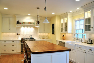 Inspiration for a mid-sized timeless u-shaped light wood floor enclosed kitchen remodel in New York with a farmhouse sink, shaker cabinets, white cabinets, marble countertops, white backsplash, subway tile backsplash, stainless steel appliances and an island