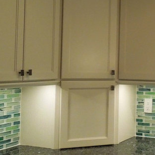 Photo of a mid-sized beach style u-shaped open plan kitchen in Charleston with an undermount sink, recessed-panel cabinets, white cabinets, recycled glass benchtops, green splashback, glass tile splashback, stainless steel appliances, ceramic floors and with island.
