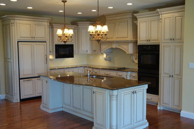 Example of a mid-sized classic l-shaped medium tone wood floor eat-in kitchen design in Chicago with a double-bowl sink, raised-panel cabinets, white cabinets, granite countertops, yellow backsplash, mosaic tile backsplash, paneled appliances and an island
