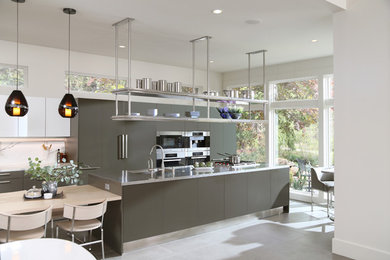 Eat-in kitchen - large contemporary galley slate floor eat-in kitchen idea in Orange County with an undermount sink, flat-panel cabinets, gray cabinets, stainless steel countertops, white backsplash, stone slab backsplash, stainless steel appliances and an island