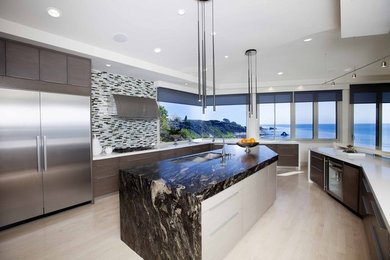 Inspiration for a large coastal u-shaped light wood floor kitchen remodel in Orange County with a double-bowl sink, flat-panel cabinets, medium tone wood cabinets, quartzite countertops, multicolored backsplash, glass tile backsplash, stainless steel appliances and an island