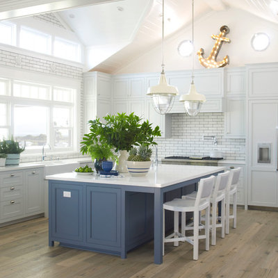 Inspiration for a large coastal l-shaped light wood floor kitchen remodel in San Diego with a farmhouse sink, shaker cabinets, blue cabinets, quartz countertops, white backsplash, paneled appliances, an island and subway tile backsplash