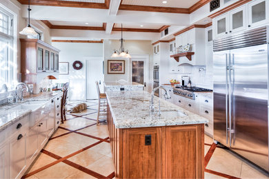 Large arts and crafts galley travertine floor and multicolored floor eat-in kitchen photo in San Diego with a farmhouse sink, shaker cabinets, white cabinets, granite countertops, white backsplash, ceramic backsplash, stainless steel appliances and an island