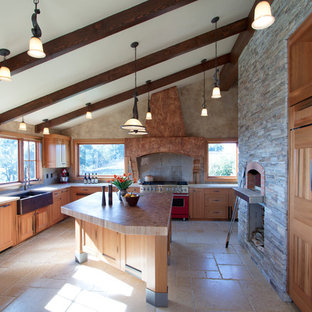 Foto di un'ampia cucina ad U mediterranea con lavello stile country, ante con riquadro incassato, ante in legno scuro, top in legno, paraspruzzi grigio, elettrodomestici da incasso e isola