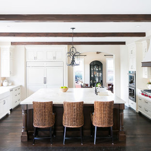 Mediterranean enclosed kitchen ideas - Inspiration for a mediterranean dark wood floor and brown floor enclosed kitchen remodel in San Diego with paneled appliances, an island, a farmhouse sink, recessed-panel cabinets, white cabinets and white countertops