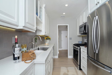 Example of a small transitional galley light wood floor and beige floor enclosed kitchen design in Los Angeles with a single-bowl sink, raised-panel cabinets, white cabinets, quartz countertops, brown backsplash, cement tile backsplash and stainless steel appliances