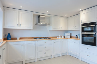 Photo of a medium sized traditional u-shaped kitchen/diner in Gloucestershire with shaker cabinets, white cabinets and wood worktops.