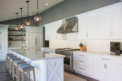 Example of a mid-sized trendy u-shaped dark wood floor and brown floor open concept kitchen design in Orange County with an undermount sink, shaker cabinets, white cabinets, marble countertops, white backsplash, subway tile backsplash, stainless steel appliances and an island