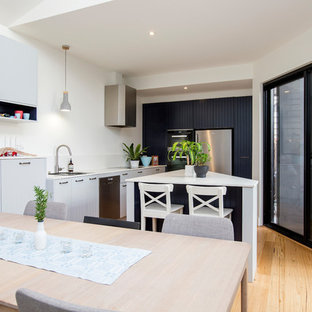 Photo of a small contemporary single-wall eat-in kitchen in Melbourne with an undermount sink, stainless steel appliances, medium hardwood floors, with island, brown floor and white benchtop.