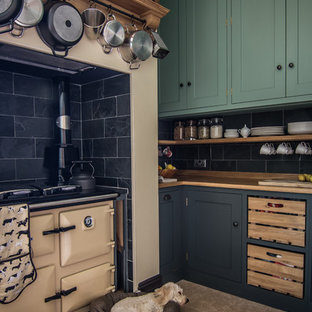 Photo of a small contemporary l-shaped eat-in kitchen in Gloucestershire with a drop-in sink, shaker cabinets, green cabinets, wood benchtops, black splashback, stone tile splashback, coloured appliances, limestone floors and no island.